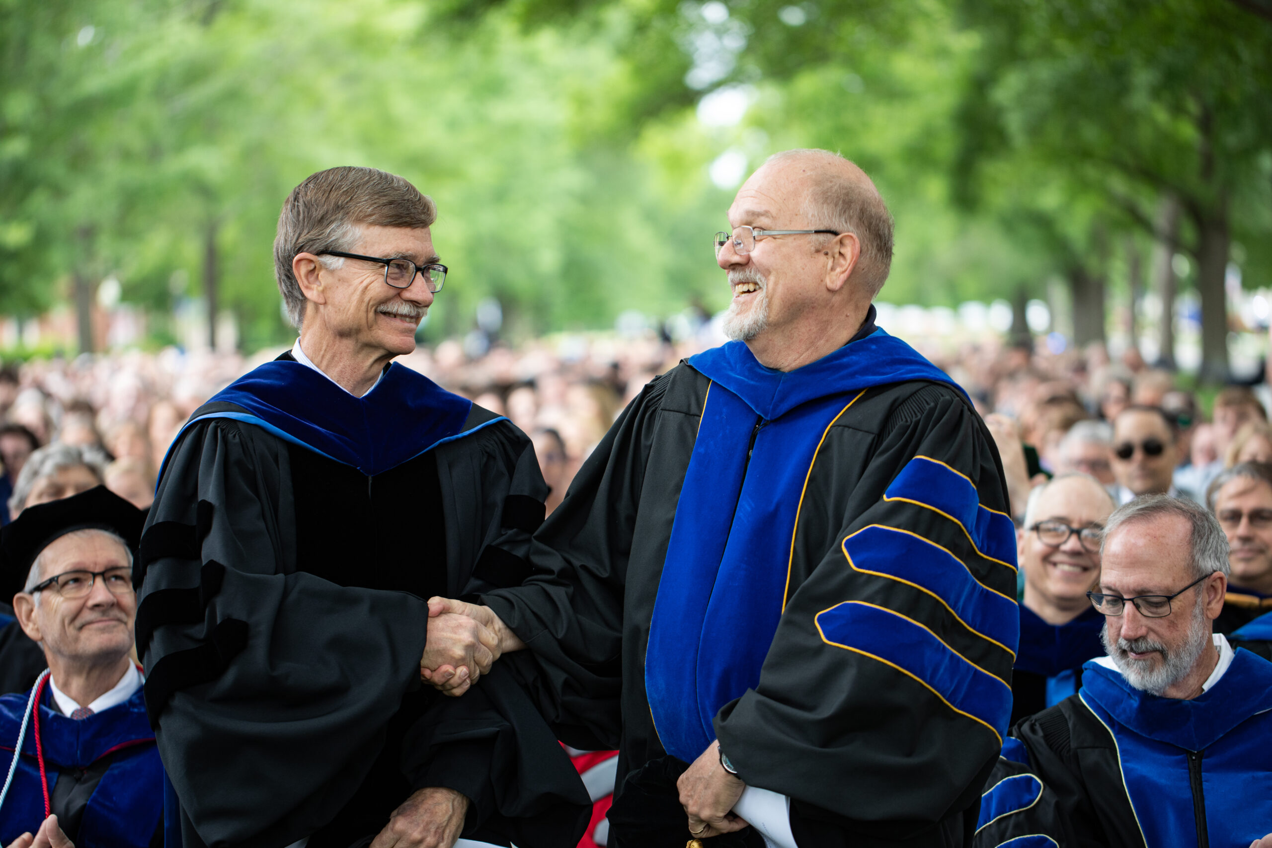 Drs. Bob Bryant and Ron Zimmerman shaking hands at graduation.